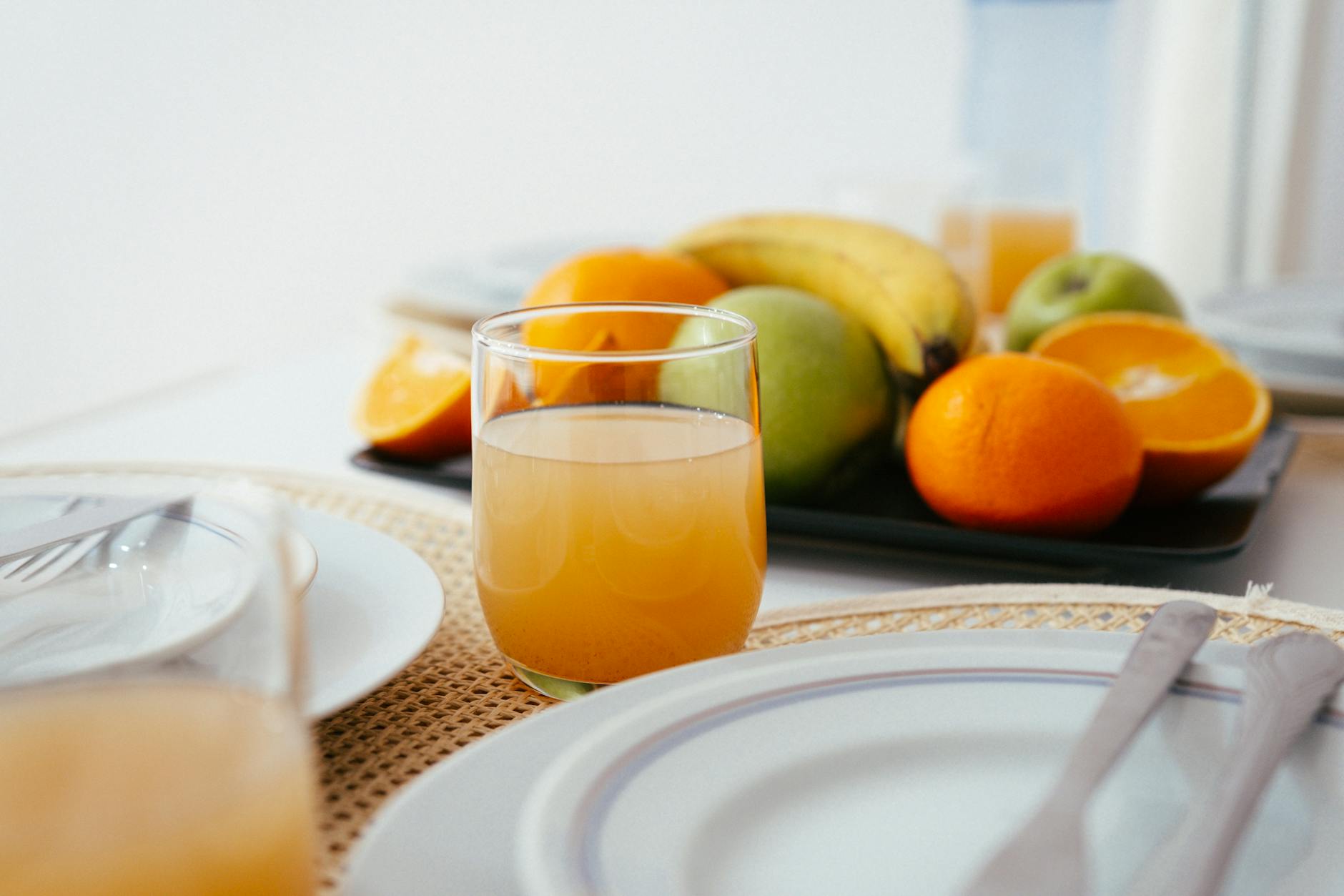 Bright and fresh breakfast setup featuring orange juice and a variety of fruits 
