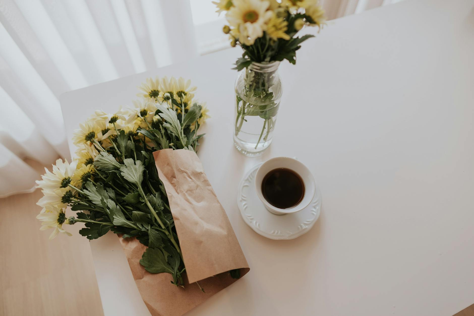 A bright morning scene with coffee and daisies on a white table, creating a fres