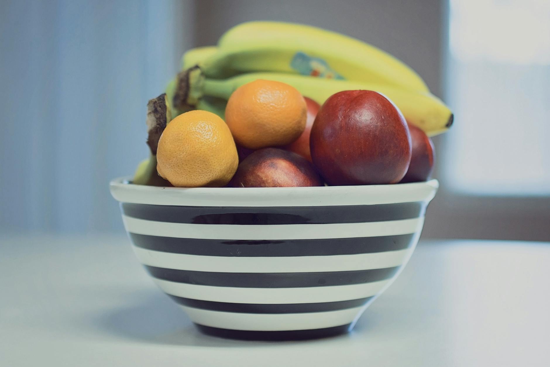 A vibrant assortment of fresh fruits in a striped bowl, ideal for healthy living