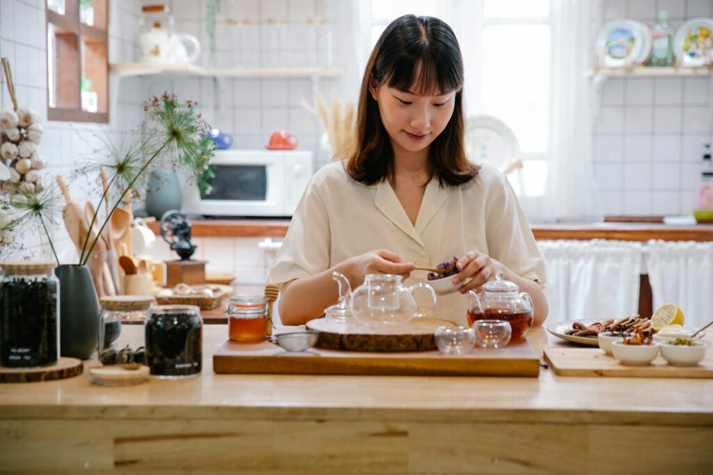 Woman preparing herbal tea with herbs and spices in a cozy kitchen setting fille
