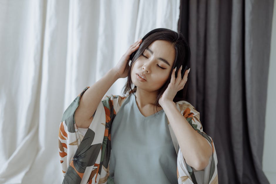 Asian woman in loungewear with headphones, eyes closed, enjoying music in a sere