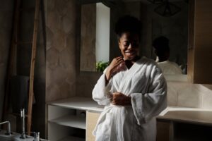 A woman in a bathrobe shares a joyful smile in a modern bathroom setting.