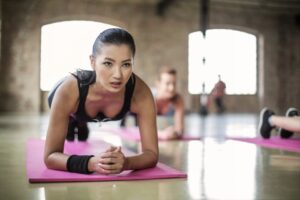 Two women engaging in a focused yoga session on pink mats in a spacious indoor s