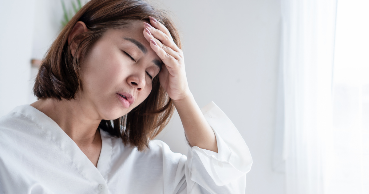 額に手を当てる女性（更年期不調・人物あり）