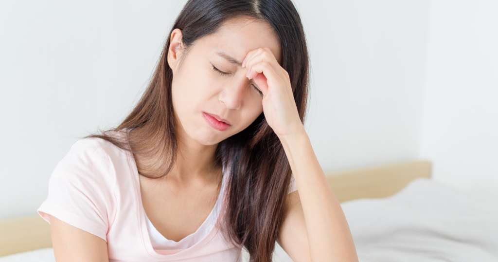 [mental] ベッドで頭痛を抱える女性（人物あり）