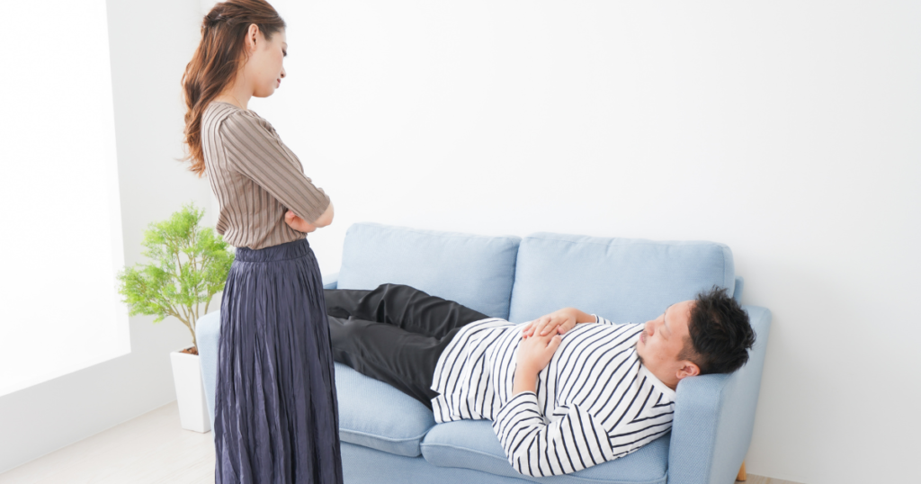 妻が横になる夫を見ている