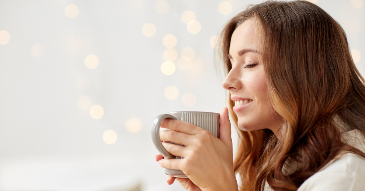 マグカップを持ちながら穏やかに微笑む女性