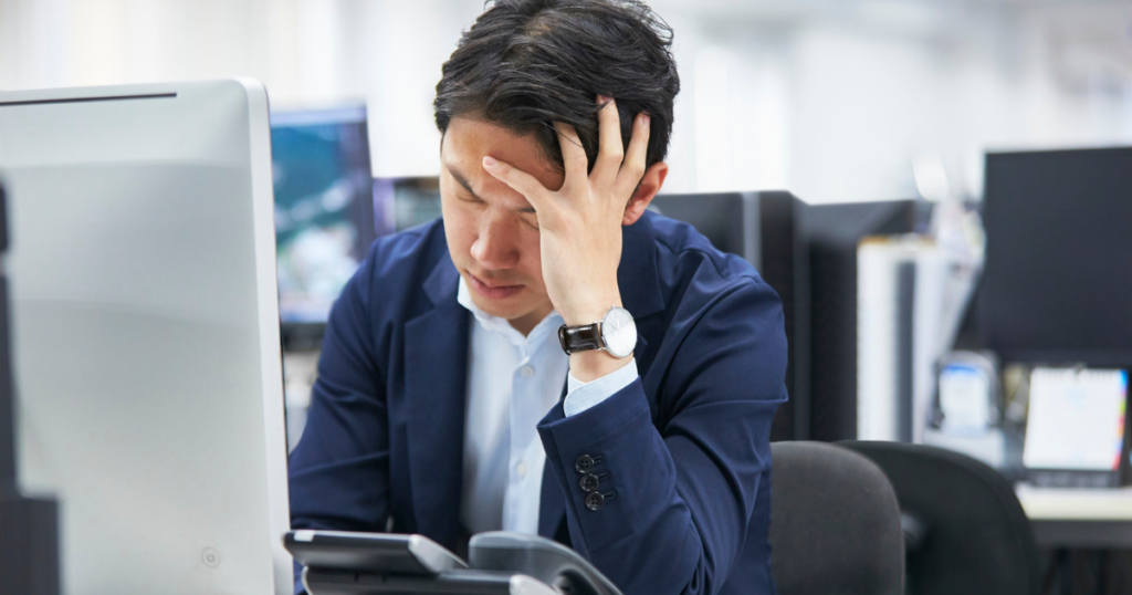 仕事中に頭を抱える男性