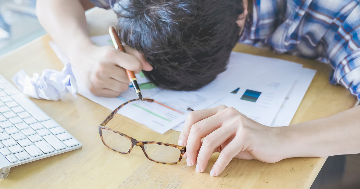 机に突っ伏して疲れた様子の男性