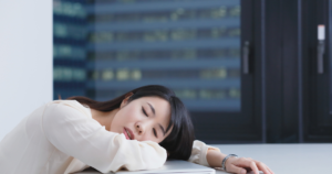 女性 机に突っ伏す 疲れ 眠気 倦怠感