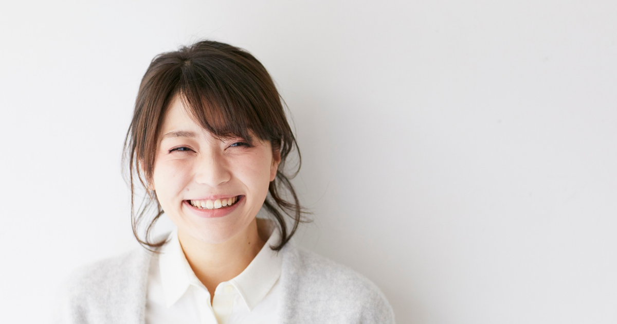 女性 笑顔 白いカーディガン 白背景 アラフィフ 清潔感