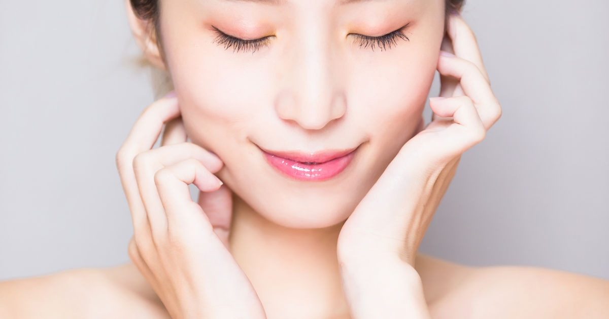 目を閉じて両手を頬に添える女性