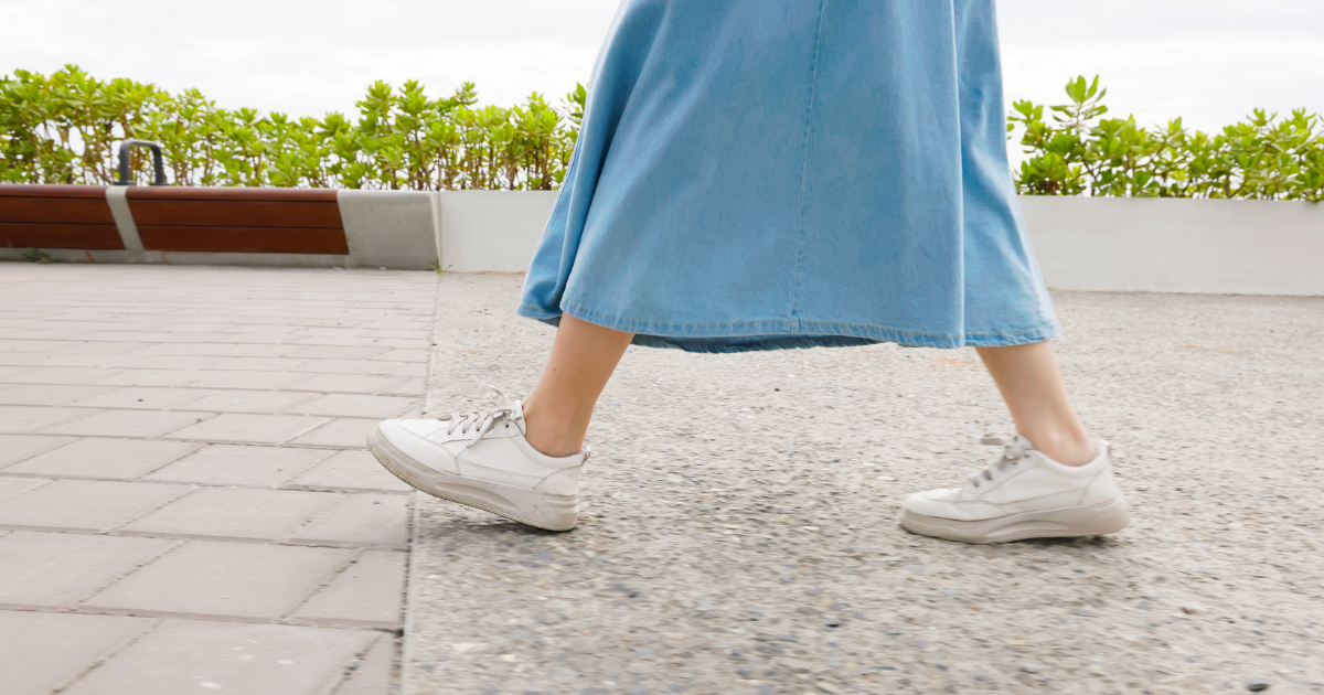 白いスニーカーで屋外を歩いている女性の足元