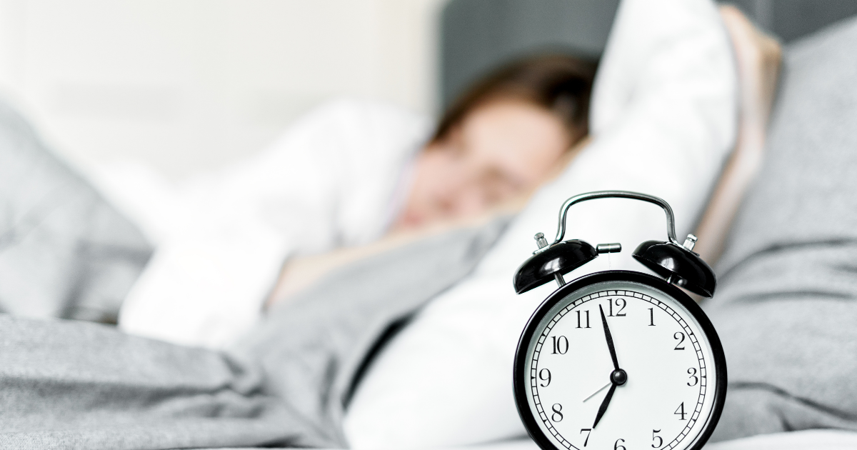 枕元の目覚まし時計と眠る女性・夜中に目が覚める