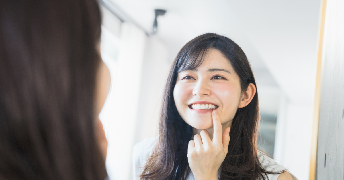 鏡の前で歯の状態をチェックする女性