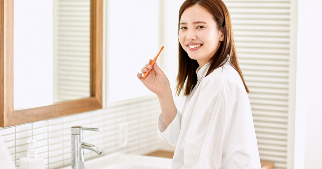 鏡前で歯磨きする女性・白シャツ
