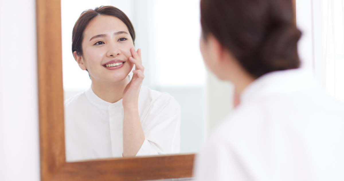 鏡の前で肌の状態を確認する50代女性