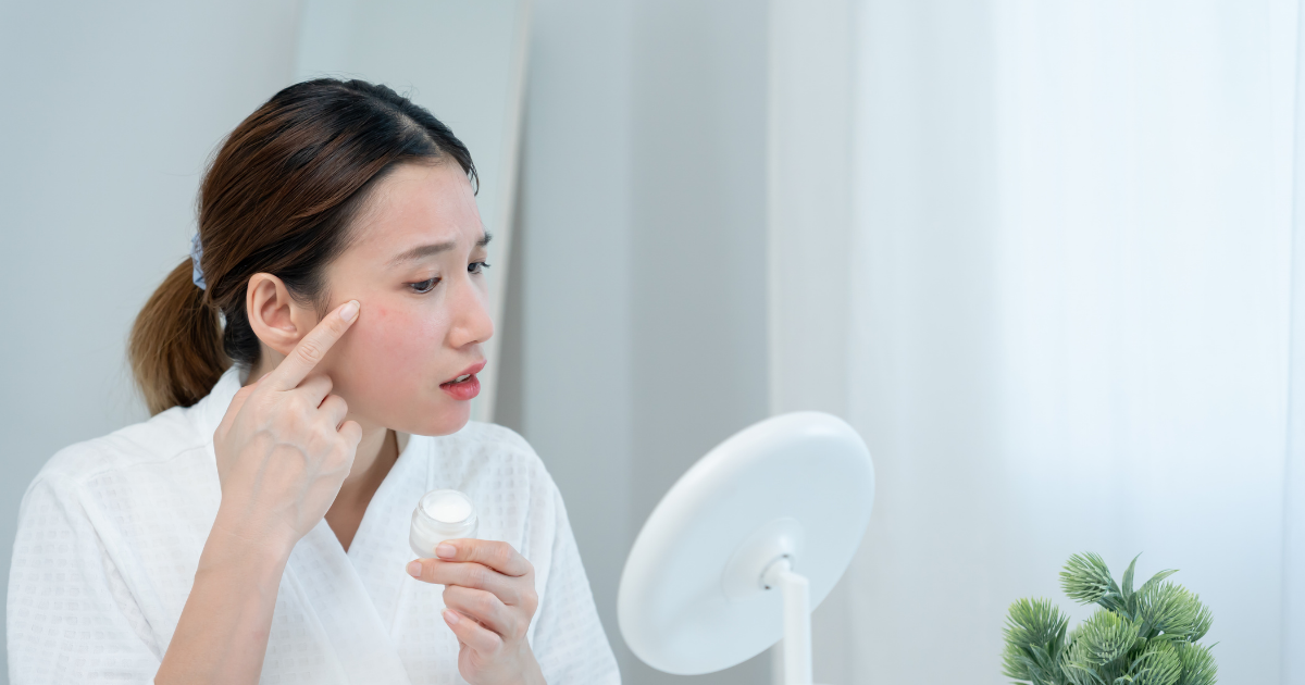 鏡の前でクリームを塗布してスキンケアする女性