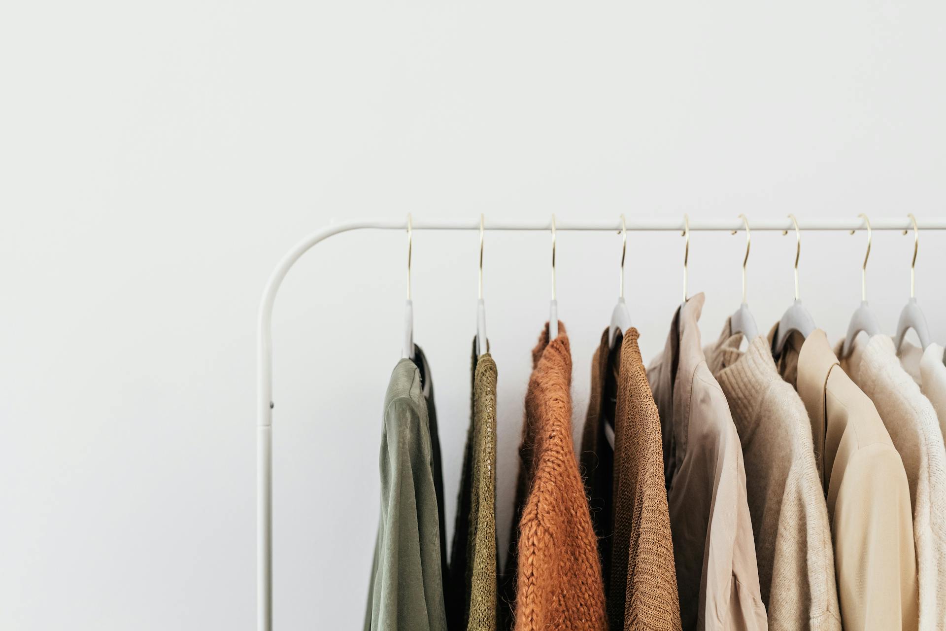 アースカラーの服が並ぶシンプルな衣装ラック