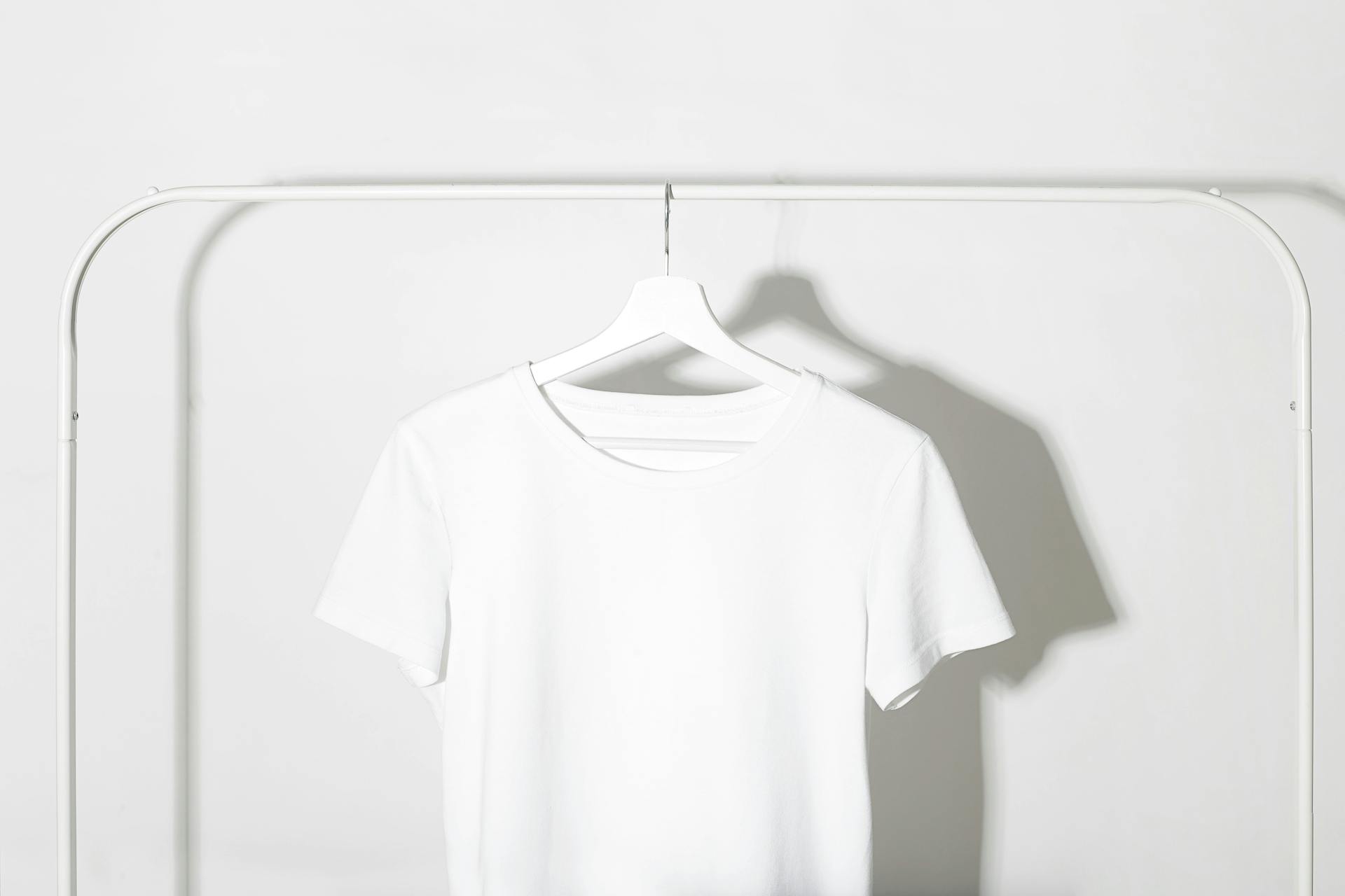 白いハンガーラックに白いTシャツがかかったシンプルなクローゼット