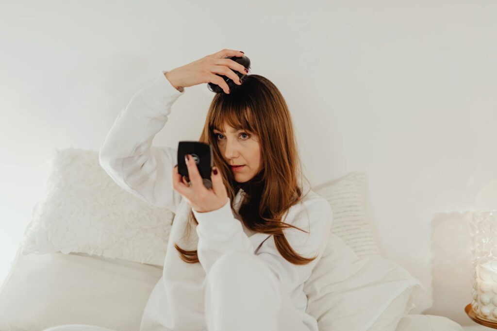 女性 ベッドでブラシ 鏡を見る 頭皮マッサージ ヘアケア