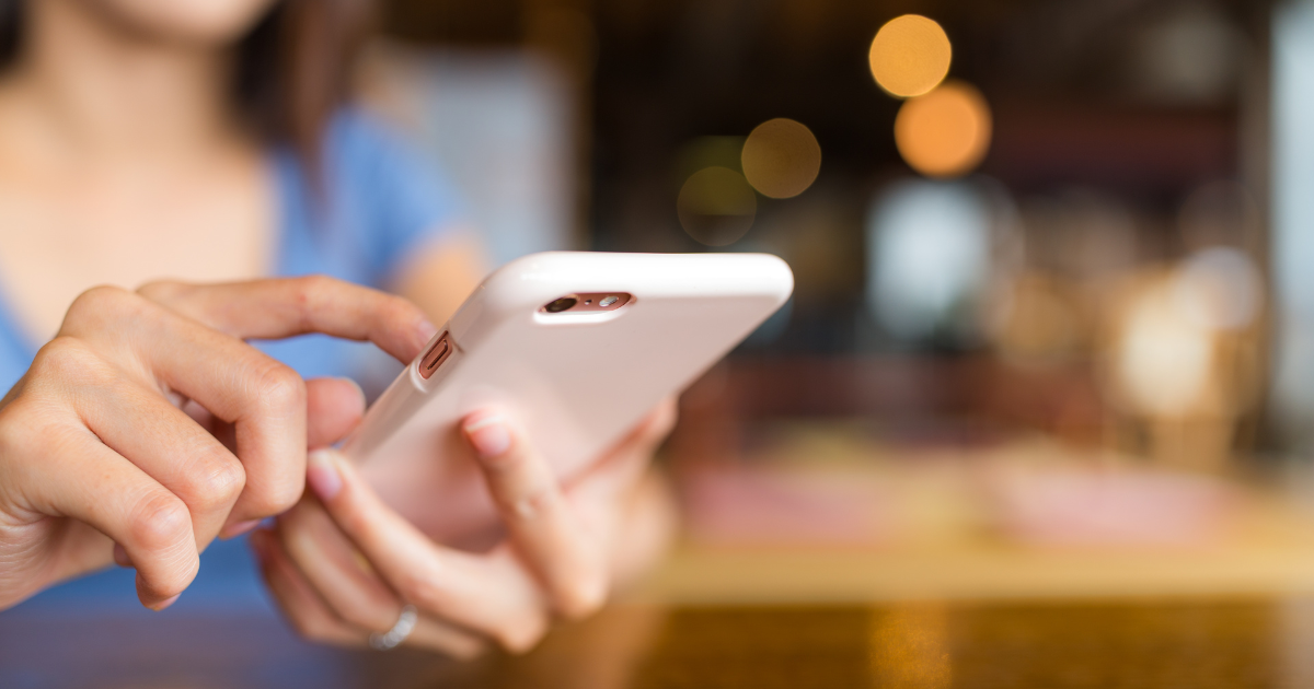 カフェでスマートフォンを手に持つ女性