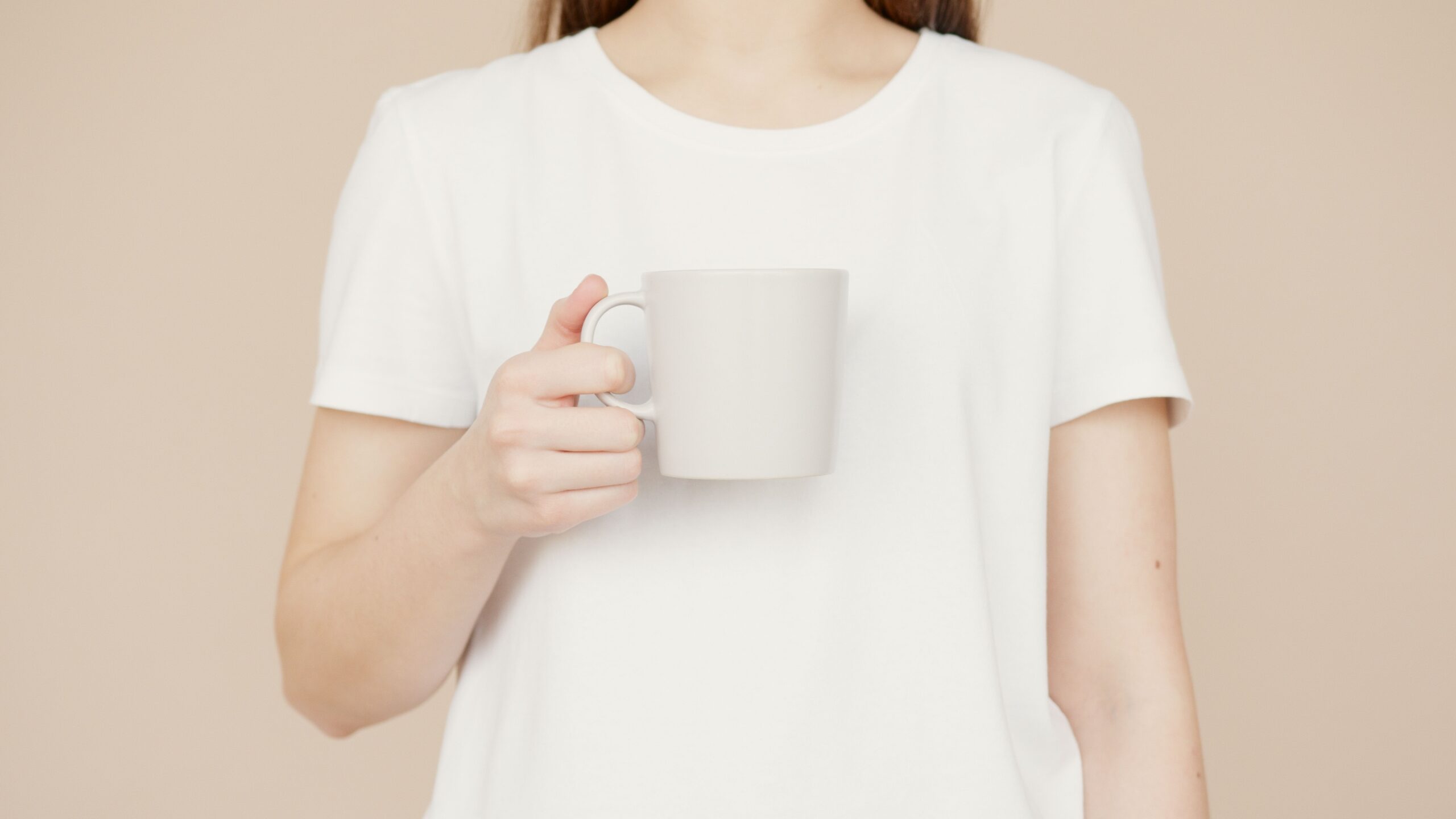 白いマグカップを持つ女性の手元