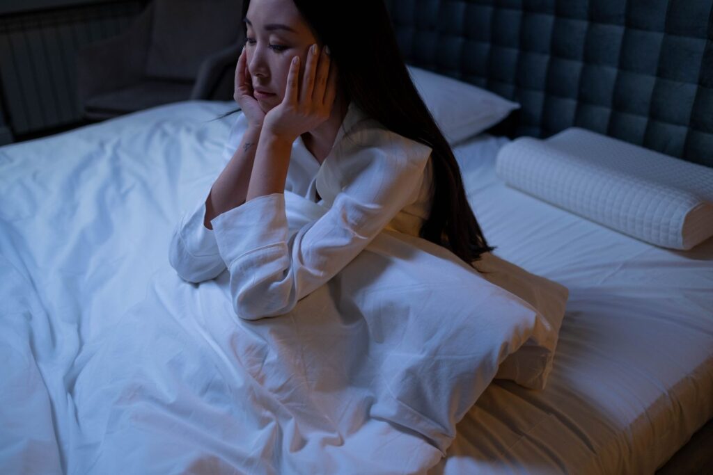 夜中に暑くて目が覚めてしまった女性がベッドで天井を見つめている